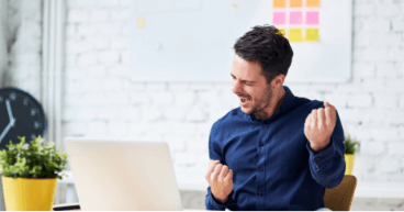 Man in front of a computer shows a gesture of success