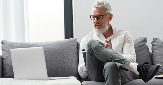 Older man sitting on a couch with a laptop